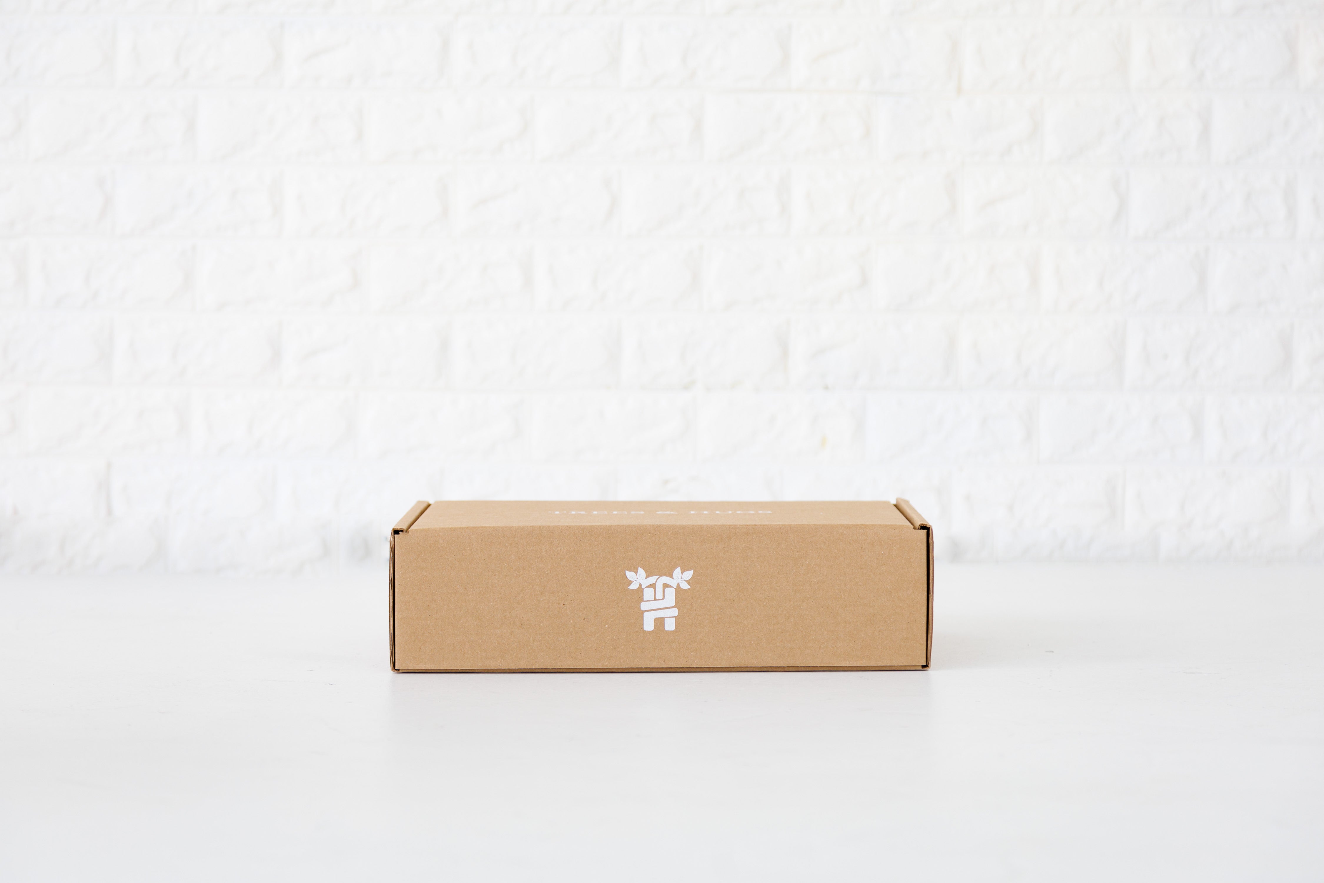 Signature seam organic cotton sheet set in a mailer box placed flat before beautiful white textured wall