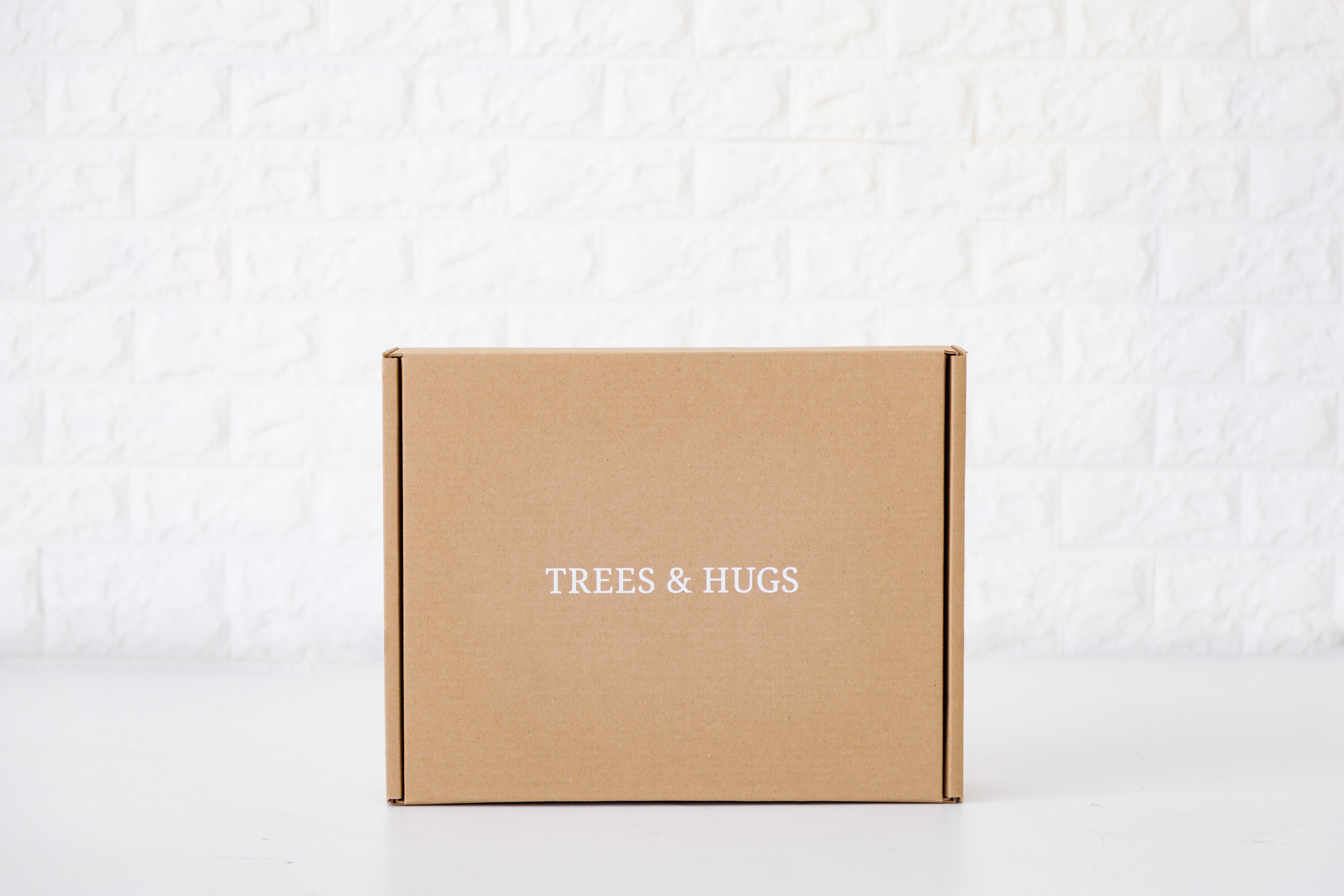Trees & hugs brown color mailer box with brand name in white letter on top of the box