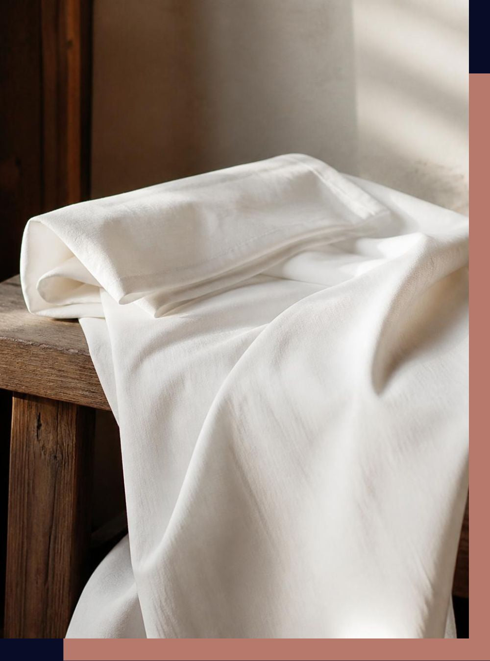 A folded and draped piece of white sheet, resting on a rustic wooden table in warm, natural light.