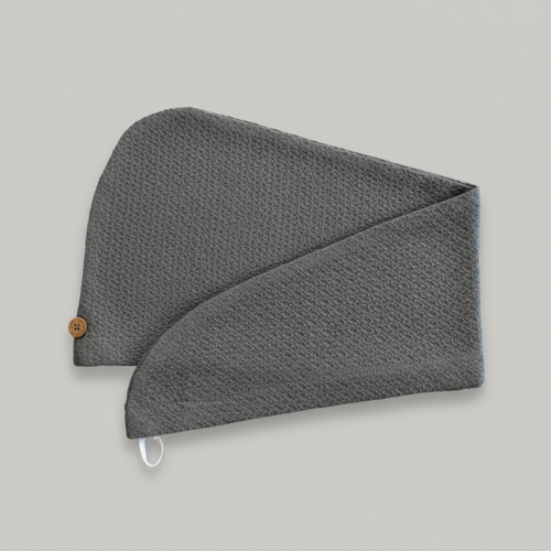 A Trees & hugs Gray textured hair wrap with a coconut shell button and white loop, folded neatly on a solid gray background.