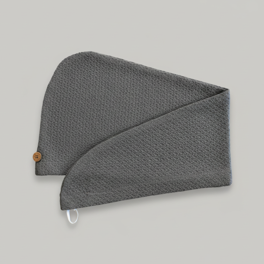 A Trees & hugs Gray textured hair wrap with a coconut shell button and white loop, folded neatly on a solid gray background.