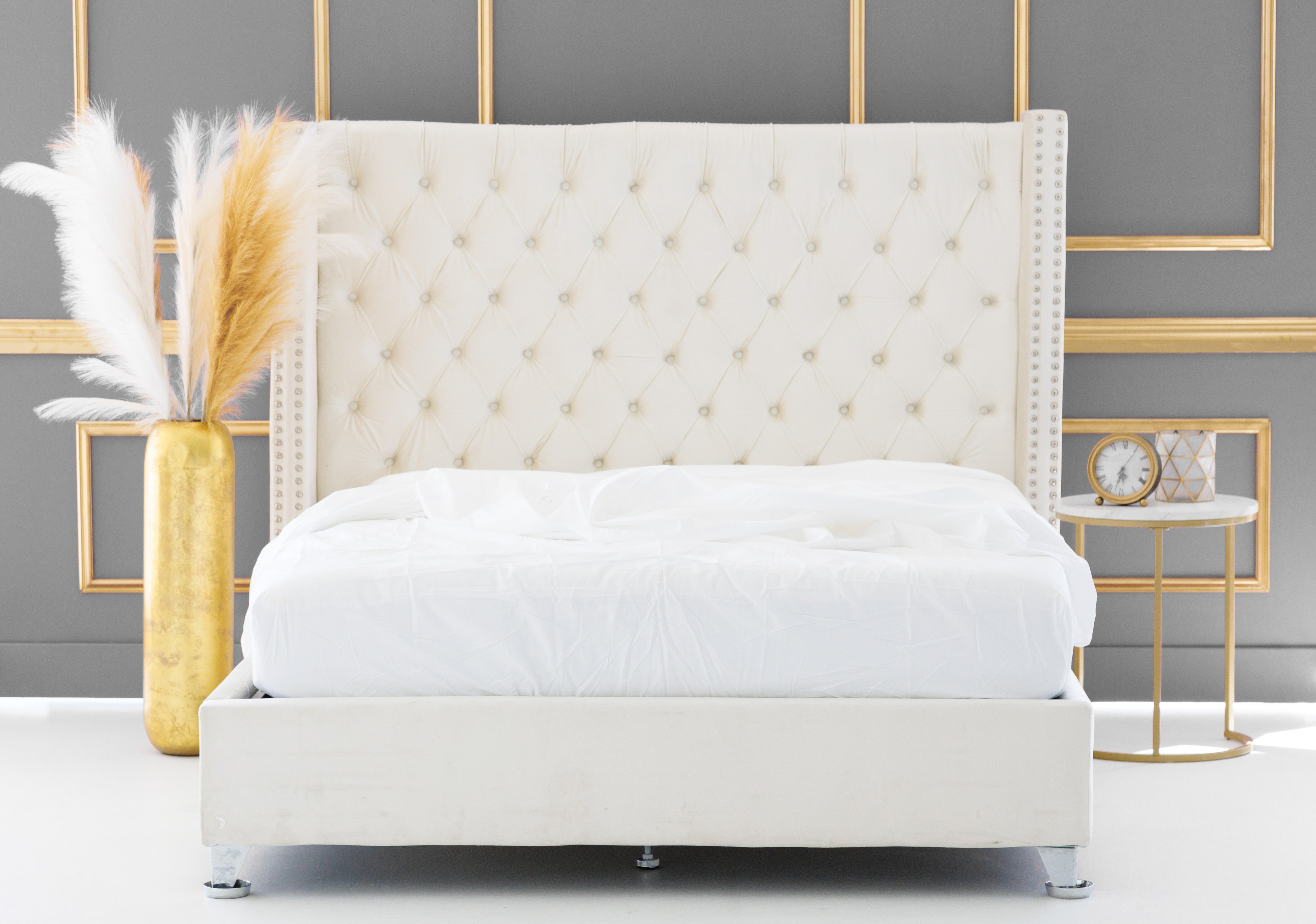 Luxury Organic Cotton sheets on a large white bed with beautiful golden vase on the side and a clock n side table