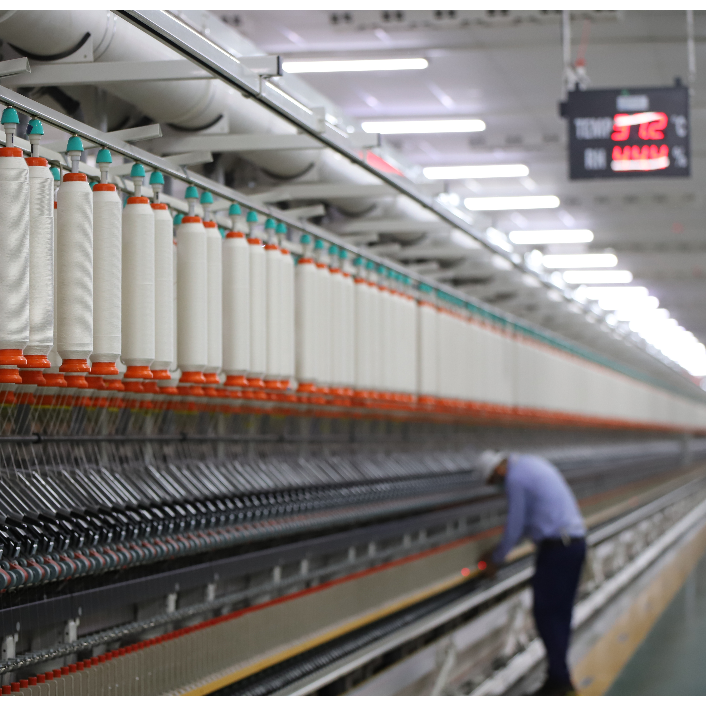 Worker working in a factory between yarn bundles
