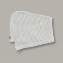 A Trees & hugs White Waffle hair wrap with a coconut shell button and white loop, folded neatly on a solid gray background.